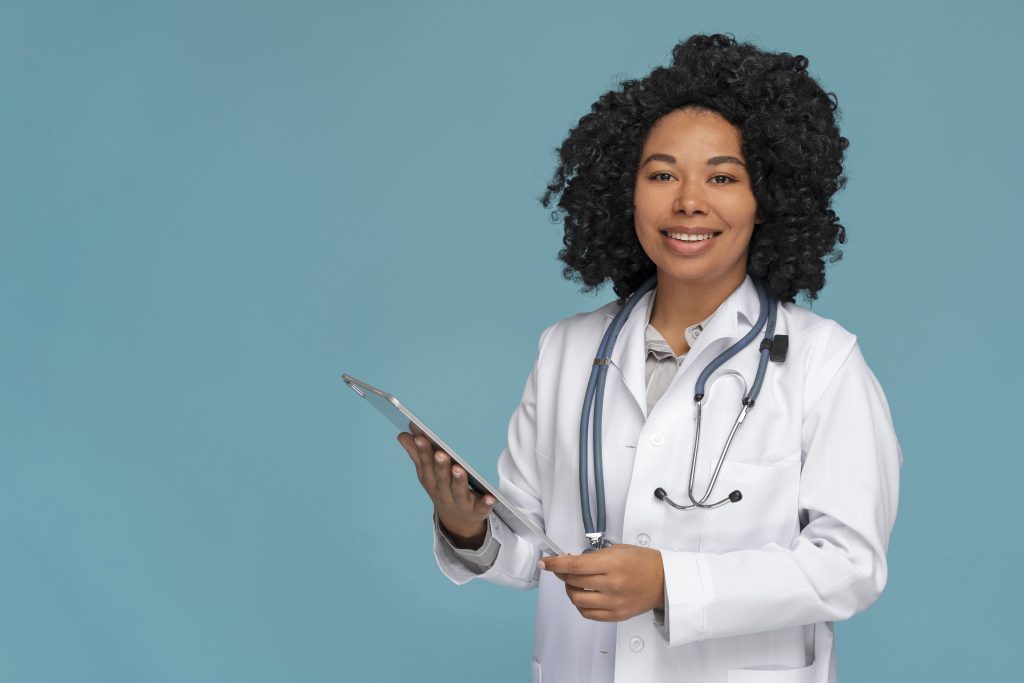 1.a. Medica com jaleco e pasta na mão sorrindo para a camera